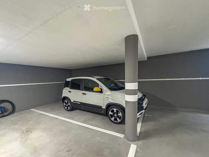 underground parking lot, car parked, gray walls, white markings, pillar