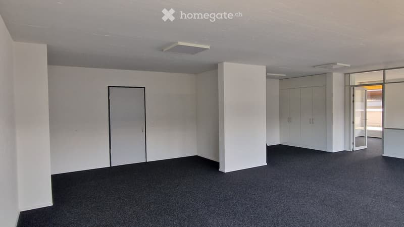 Empty room with white walls, black carpet, and a single door. No furniture or equipment is present.