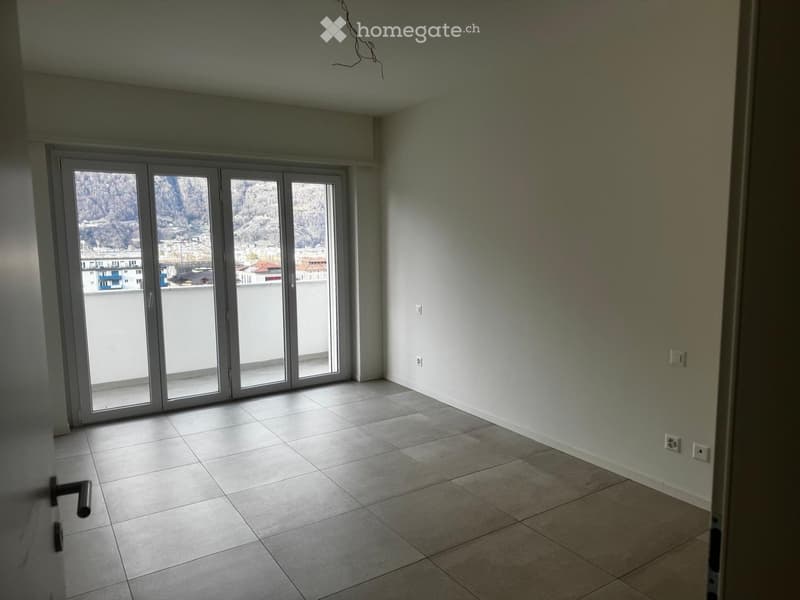 Empty room, tiled floor, sliding glass doors leading to a balcony, mountain view, white walls, power outlets, clean and unfurnished.