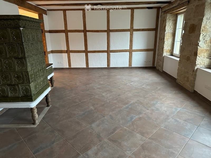 an empty room with tiled flooring, white walls, and wooden panels