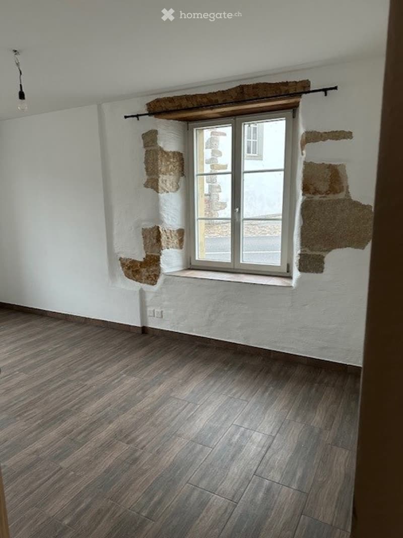 Empty room with white walls, wooden floor, a window with stone frame, wall plugs