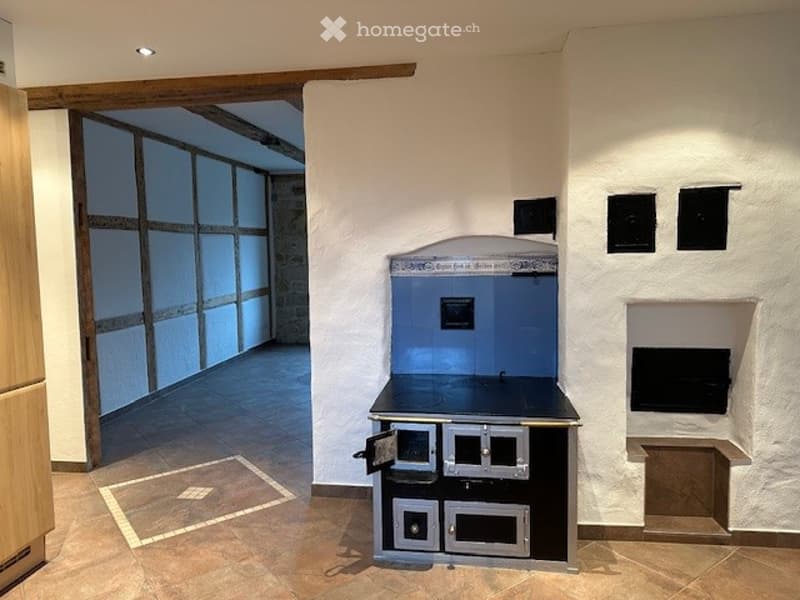 Tiled floor, old style oven, open doorway, cabinets, tiled oven, fireplace