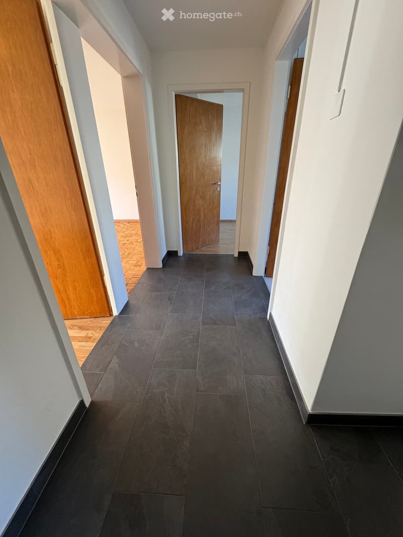 Empty hallway with tiled floor, wooden doors