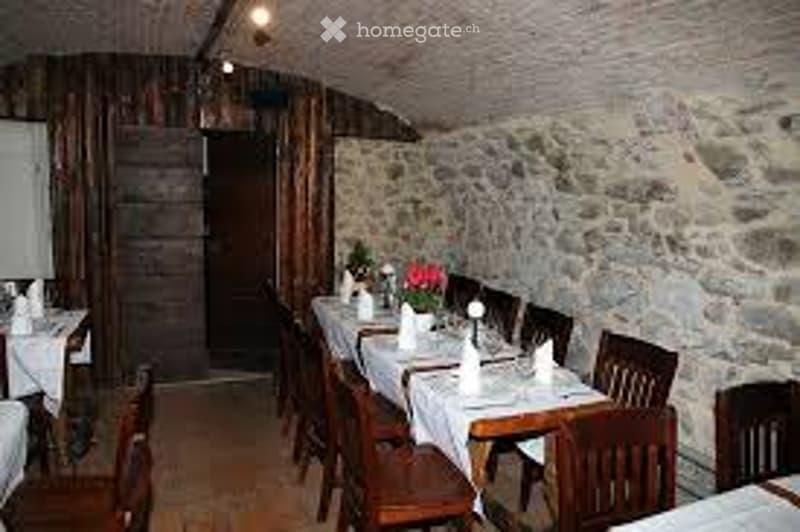 Stone walls, wooden ceiling, long dining table, wooden chairs, white tablecloths