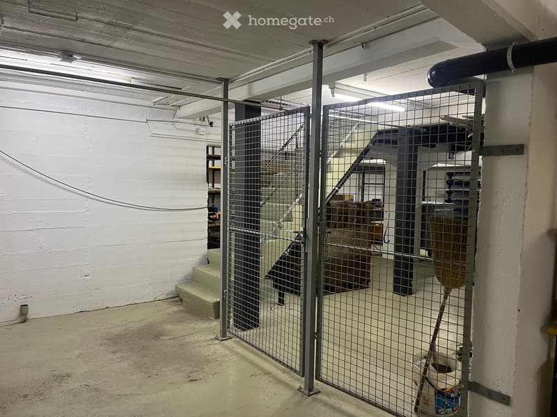 Empty storage area with metal gate, staircase, and shelves in the background