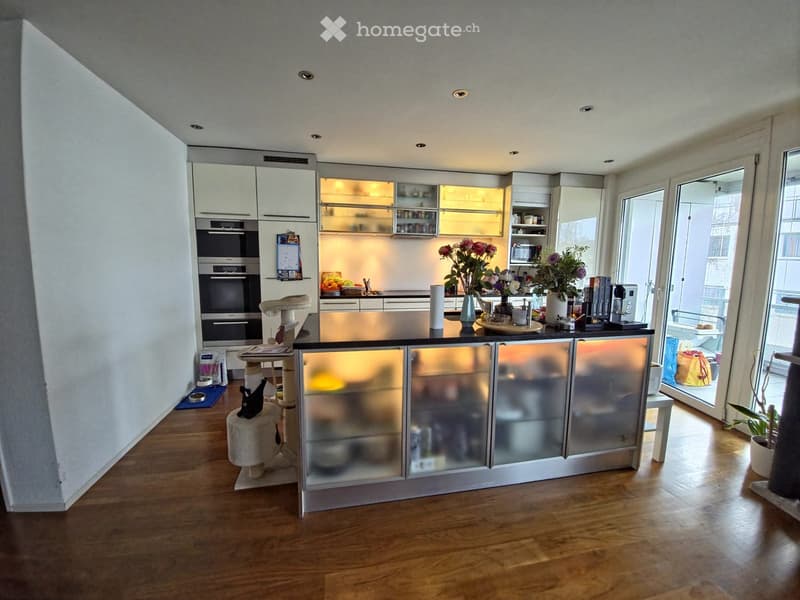 modern kitchen, white cabinets, stainless steel countertop, glass front cabinets, microwave, refrigerator, dishwasher, dining table, glass doors leading to balcony