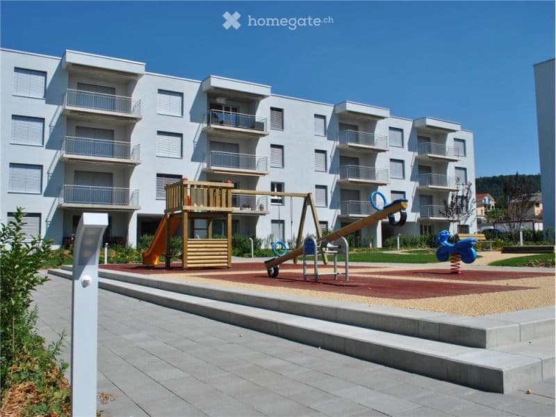 modern apartment building with balconies, children's playground with slide and swing
