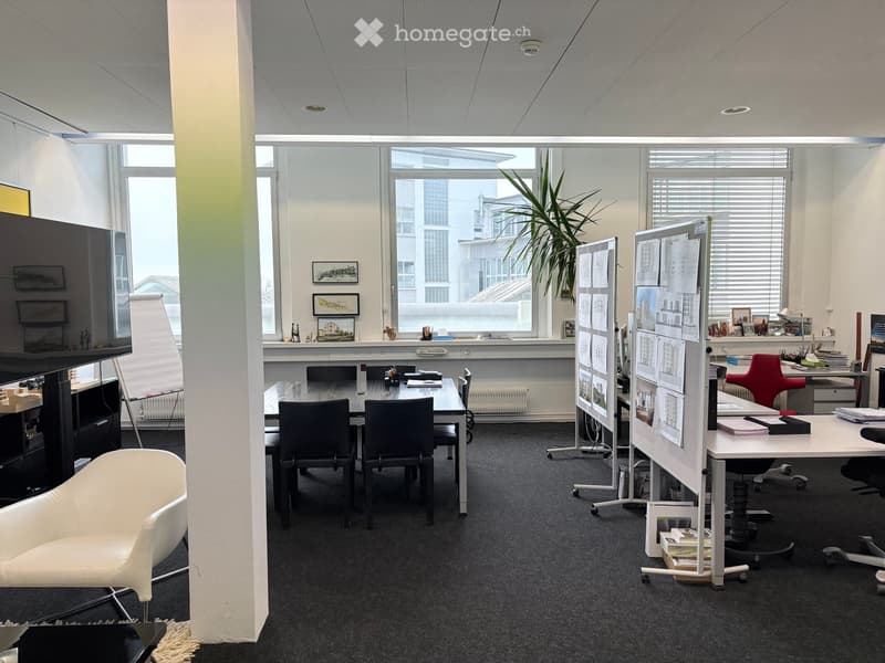 Office with large windows, a conference table, framed artwork, floor radiator, office chairs, white presentation stand, desk, whiteboard