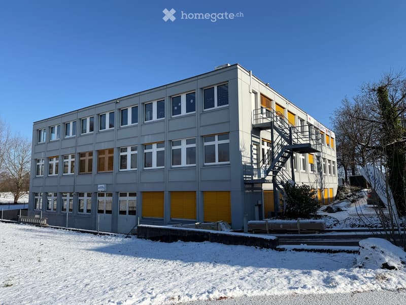 two story building, yellow roll-up doors, gray exterior, windows, staircase, snow-covered ground