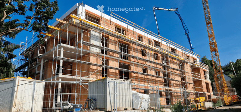 under construction building with scaffolding, cranes on site