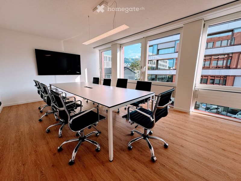 modern, light wood floor, black swivel chairs, white conference table, mounted flat-screen TV, large windows, bright