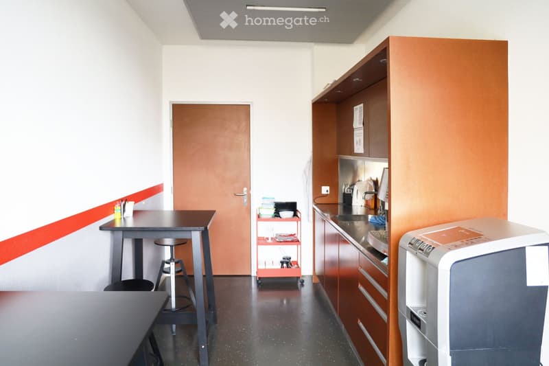 Small kitchen with tables, stools, a door, shelves, a microwave, and a coffee machine