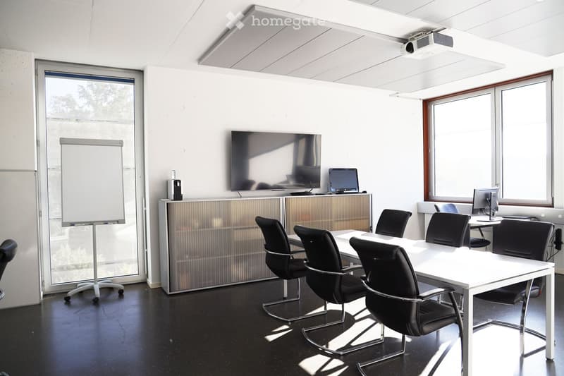 Office conference room with large windows, flat screen TV, projector, whiteboard, and black office chairs.