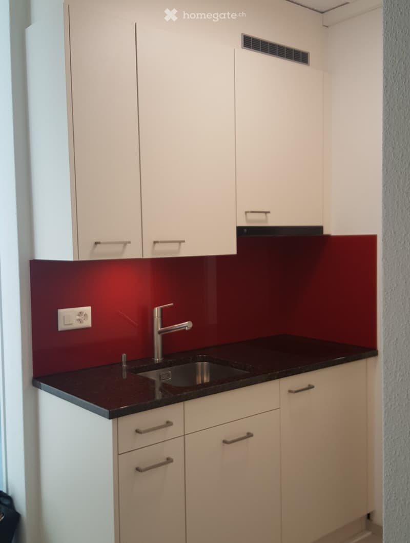 modern kitchen with white cabinets, red wall, black countertop, stainless steel sink, silver faucet, electrical outlet