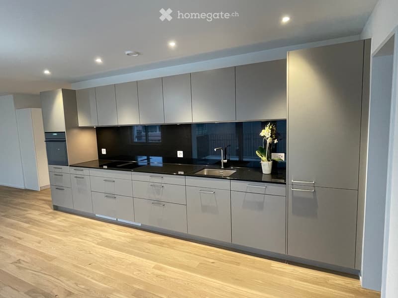 modern kitchen, sleek cabinetry, black countertops, stainless steel sink, gas stove, built-in oven, floor-mounted lights