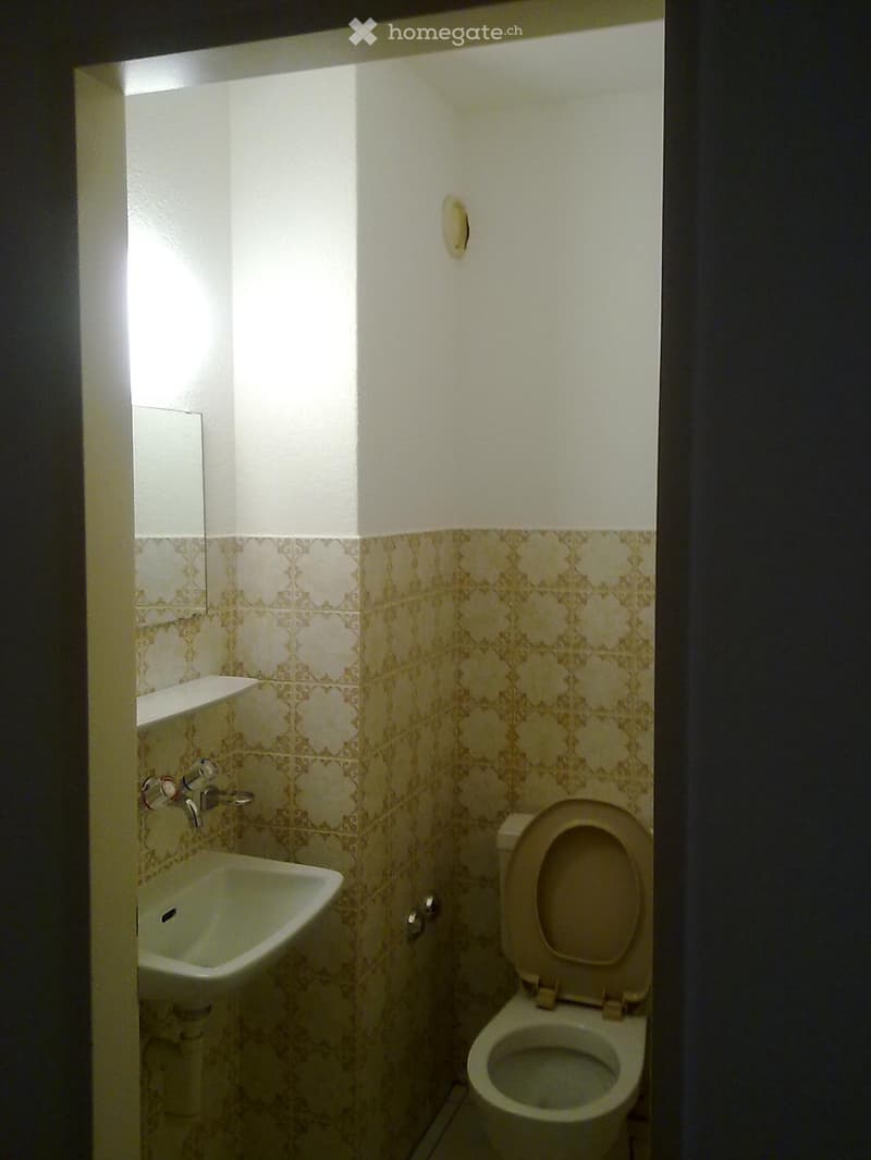 Small bathroom with white tile, mirror on wall, sink with faucet, toilet, white walls