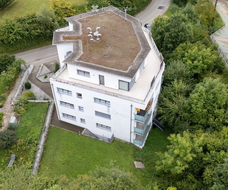 4 story house, white exterior, multiple balconies, green roof, surrounded by trees