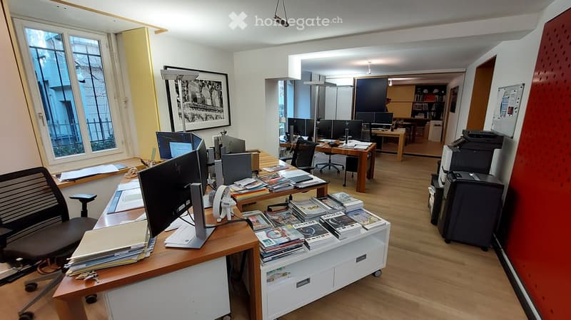 Spacious office with desk, computers, books, office chairs, printer, bulletin board