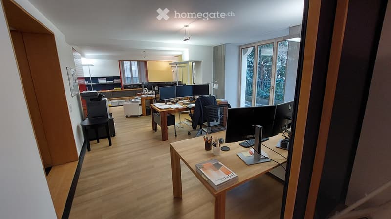 desks with monitors, office chairs, table with book, floor lamps