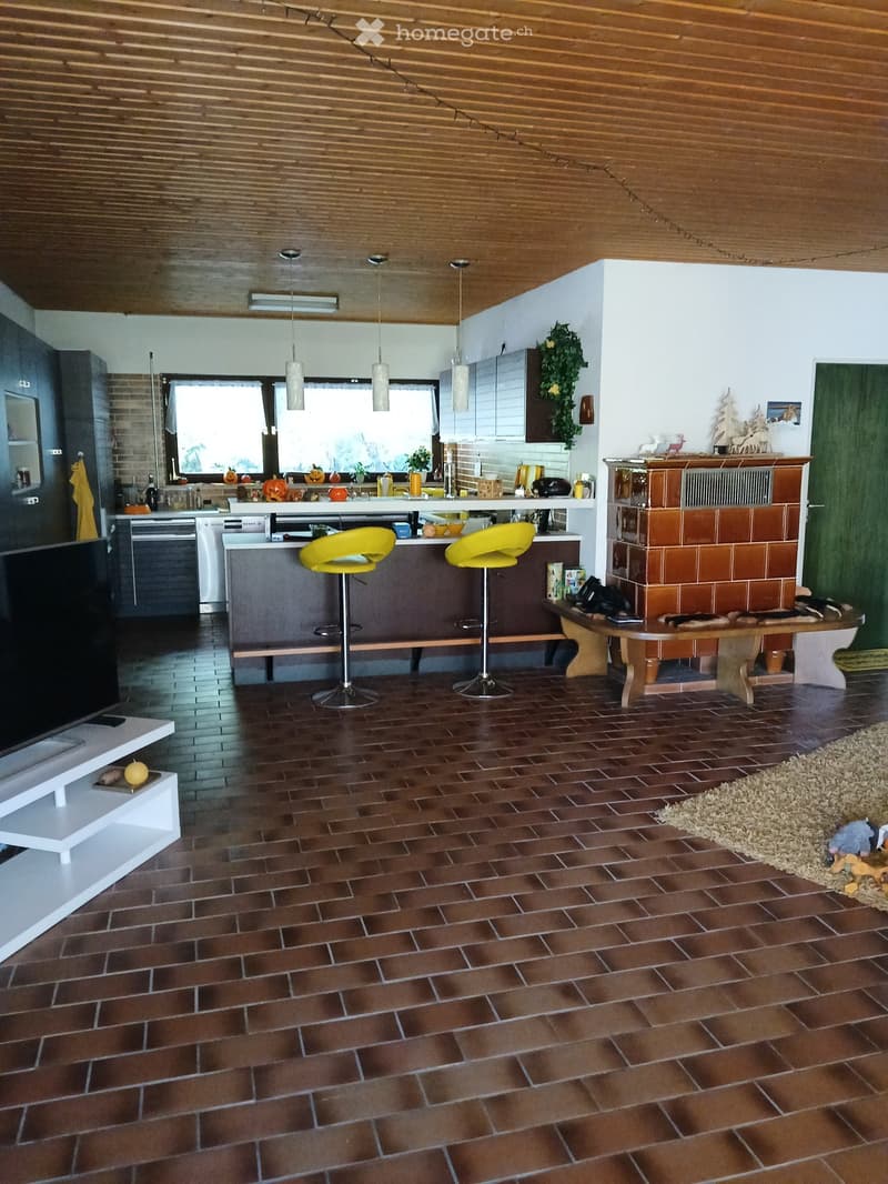 living room, wooden ceiling, fireplace, tiled floor, modern furniture, yellow bar stools, wooden desk, TV, and white shelf