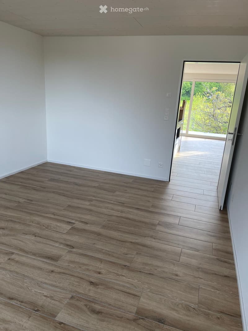 Unfurnished Room. Empty room with wooden flooring and white walls, featuring an open doorway leading to a balcony or outdoor area.