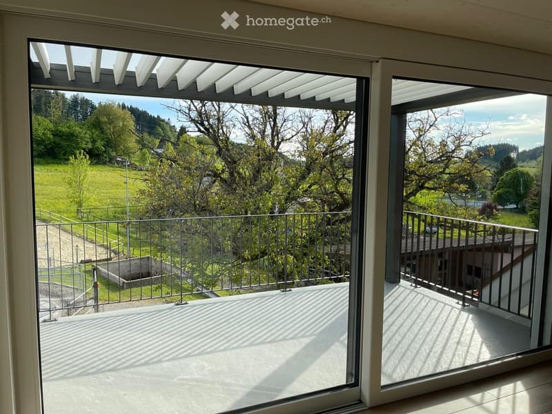 Balcony / Terrace. Balcony with large glass doors, metal railing, and scenic view of green fields and trees.