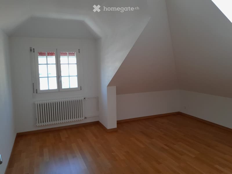 Empty room with wooden floor, white walls, small window with white frame, white radiator
