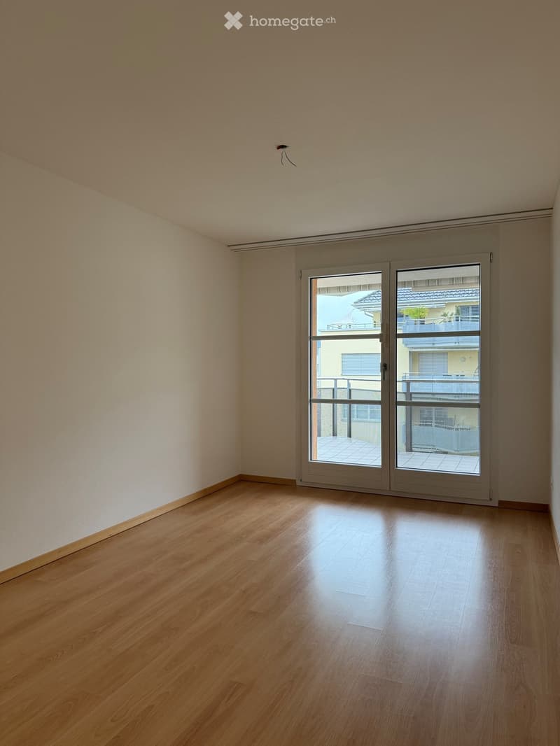 Unfurnished Room. Empty room with wooden flooring and large sliding glass doors leading to a balcony.