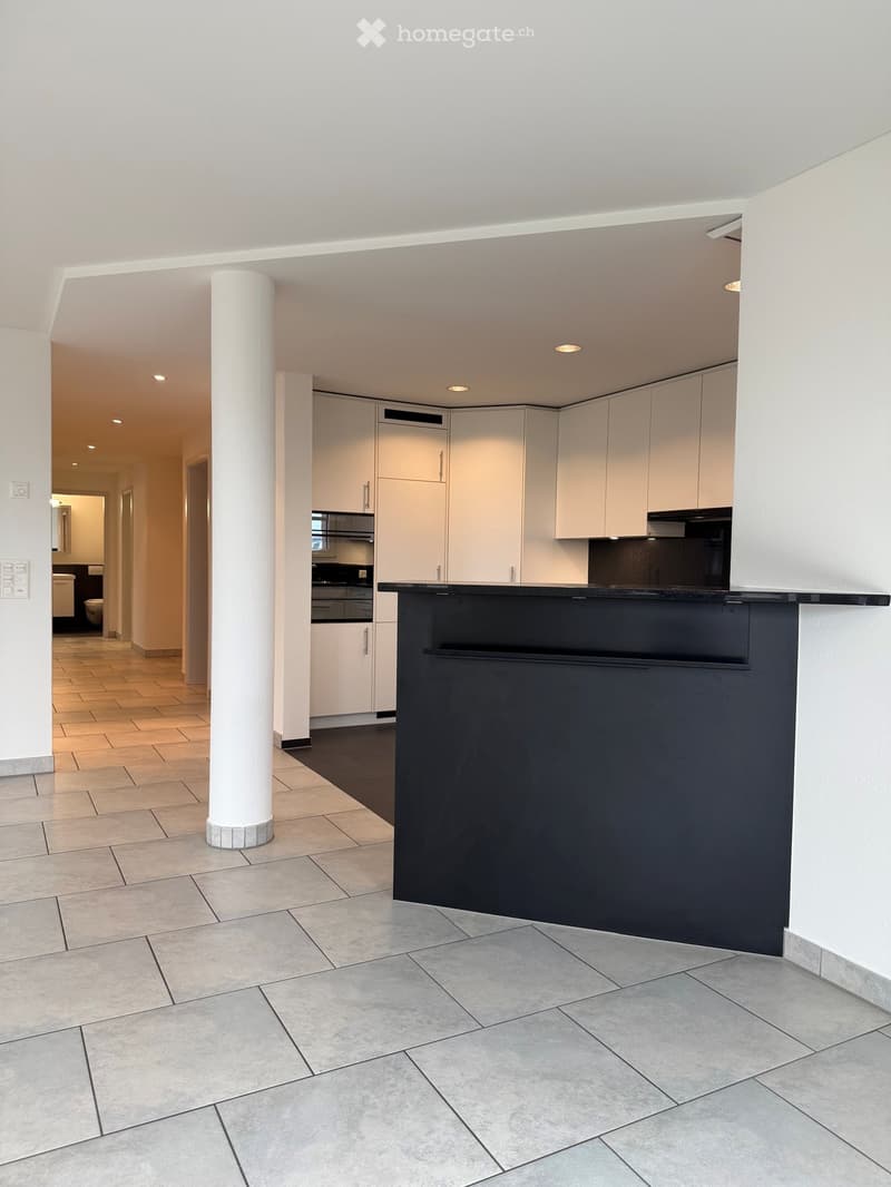Kitchen. Modern kitchen with white cabinets, a black countertop, and an integrated oven. The space features tiled flooring and recessed lighting.