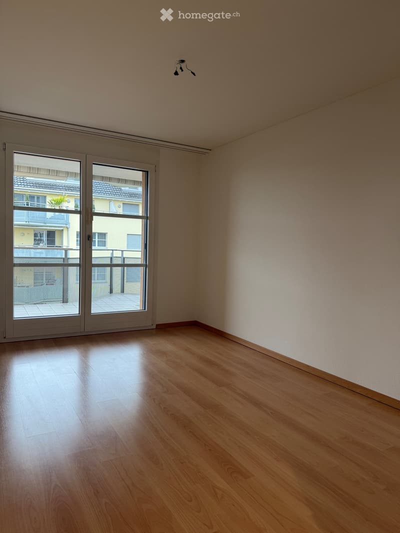 Unfurnished Room. Empty room with wooden flooring, large sliding glass doors leading to a balcony, and light-colored walls.