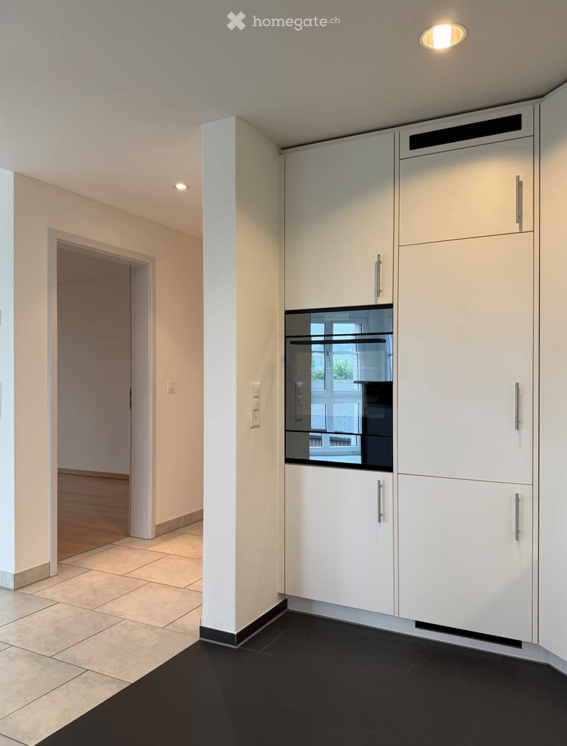 Kitchen. Modern kitchen with white cabinets, stainless steel appliances, black tiled floor, and recessed lighting.