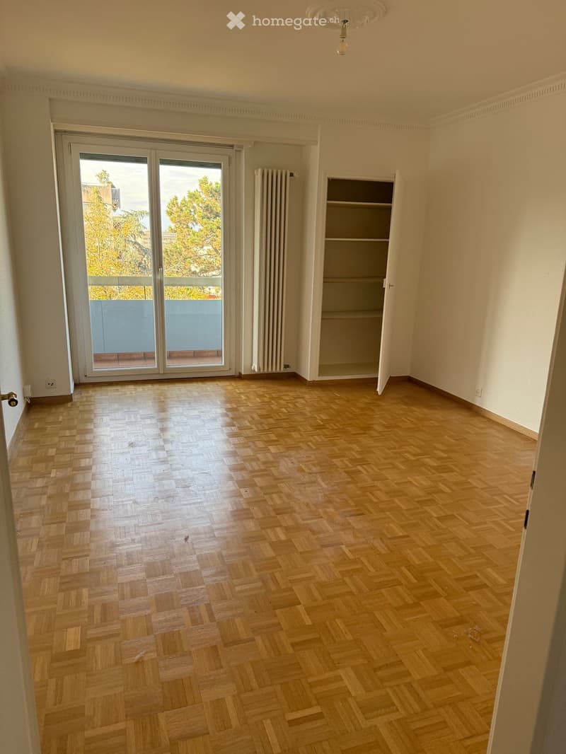 Empty room with parquet floor, sliding glass doors, wardrobe, radiator
