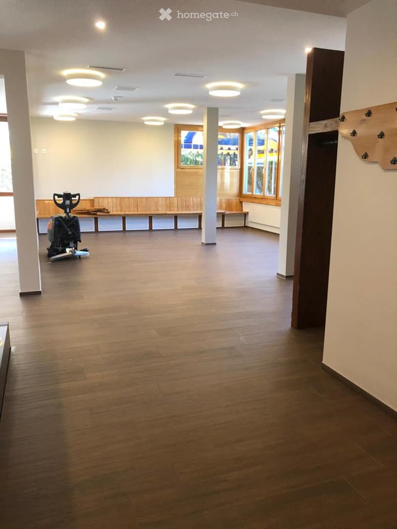 Wooden floor, large room, wooden benches, white ceiling with circular lights