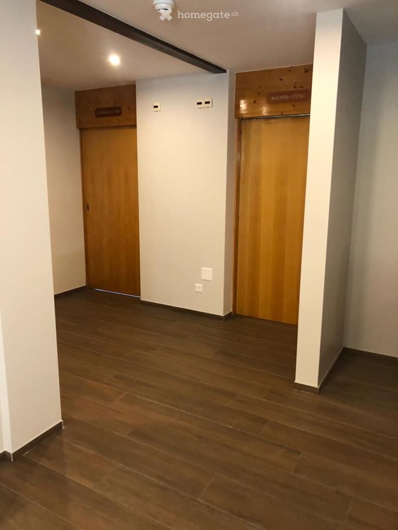 corridor with wooden flooring, 2 doors on both sides, and white walls