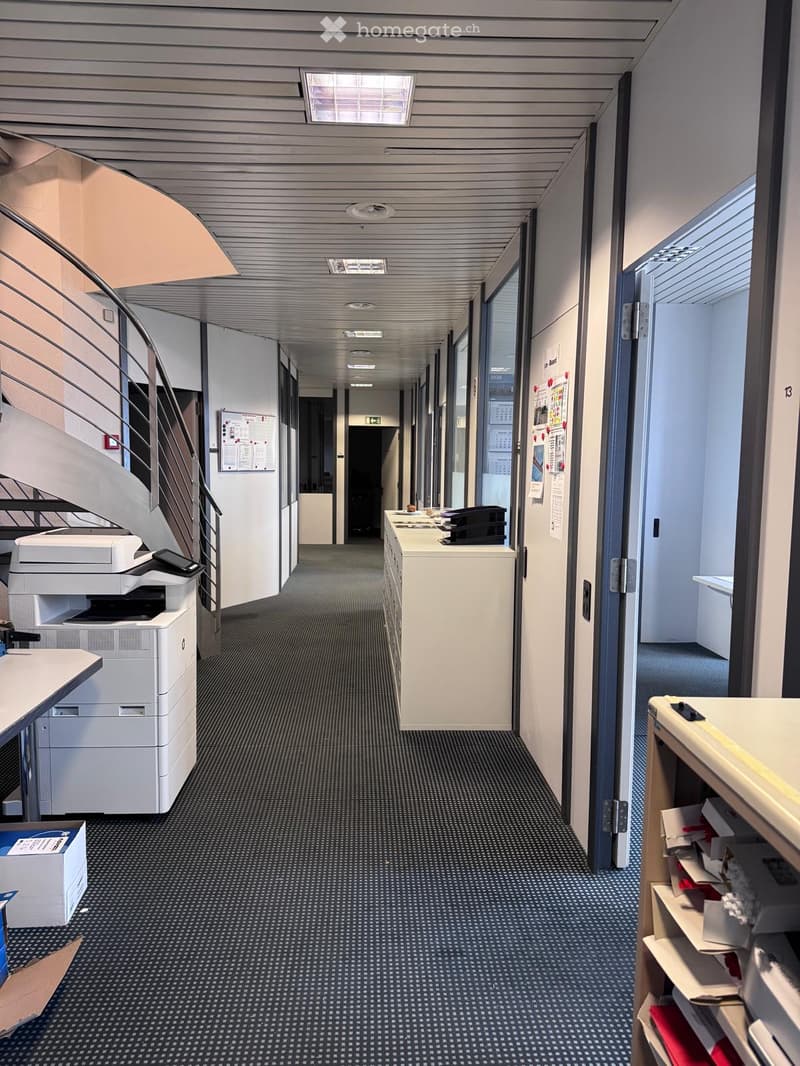 Corridor with printers and cabinets, spiral staircase, exit sign, lights