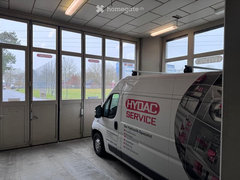 Entrance with big double doors and windows, ceiling mounted fluorescent lights, white van