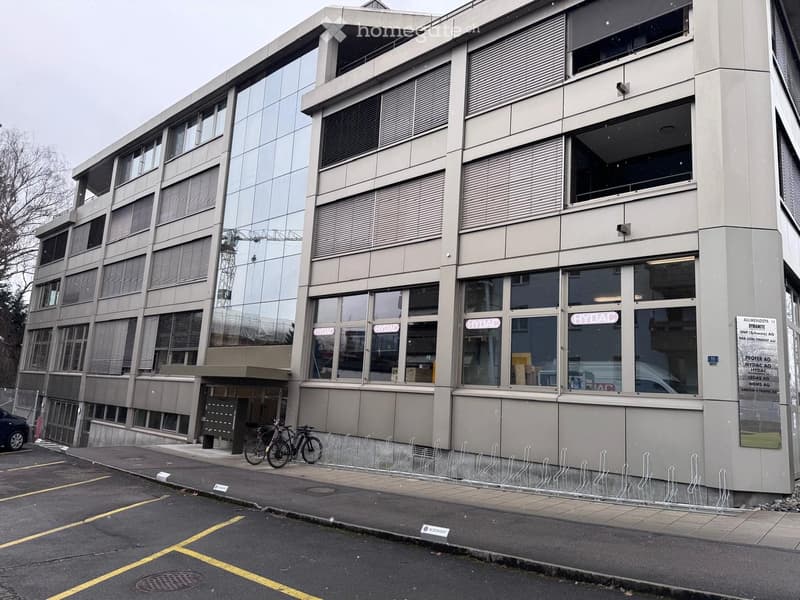 Multi-story office building with glass facade, multiple floors, two bicycles parked outside