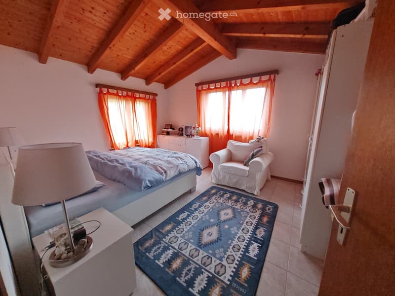 bedroom with bed, white bedhead, lamp, nightstand, rug, white cabinet, chair with pillow