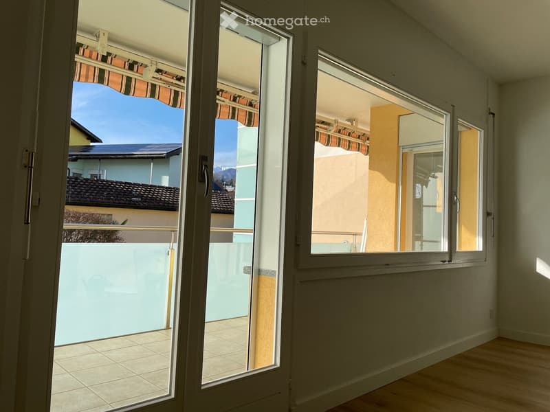 white walls, white ceiling, tiled floor, large windows, balcony with retractable awnings