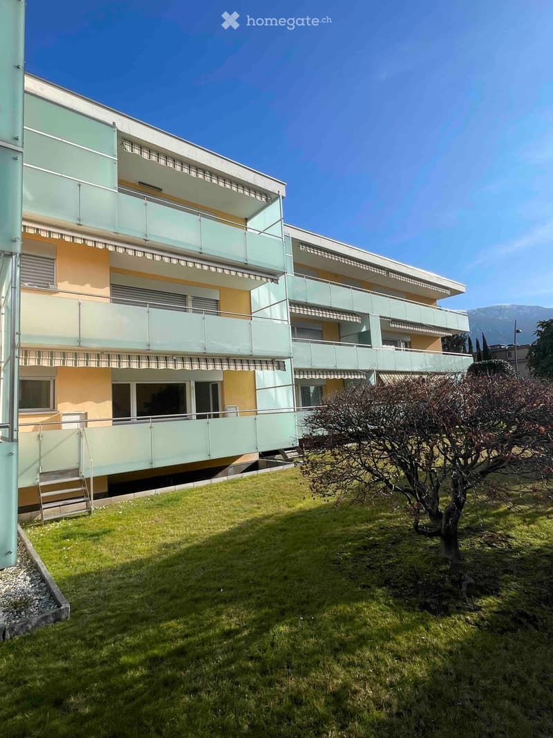 3 story building, beige exterior, white railing, balconies with glass railing, glass door, green grass