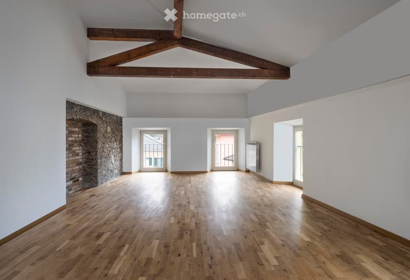 open room with wooden floors, brick fireplace, and wooden truss ceiling