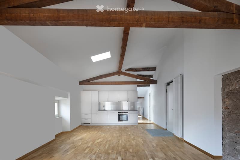 raised ground floor, wooden ceiling, wooden floor, white walls, kitchen with white cabinets and stainless steel oven, window with brick wall