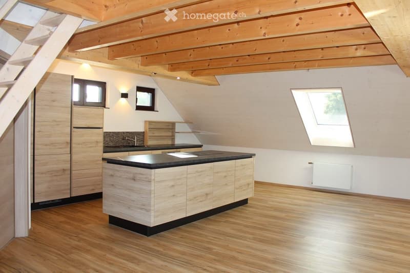 Kitchen. Modern kitchen with wooden cabinets, a central island, and a sleek black countertop. The space features exposed wooden beams on the ceiling and large windows, including a skylight, allowing ample natural light.