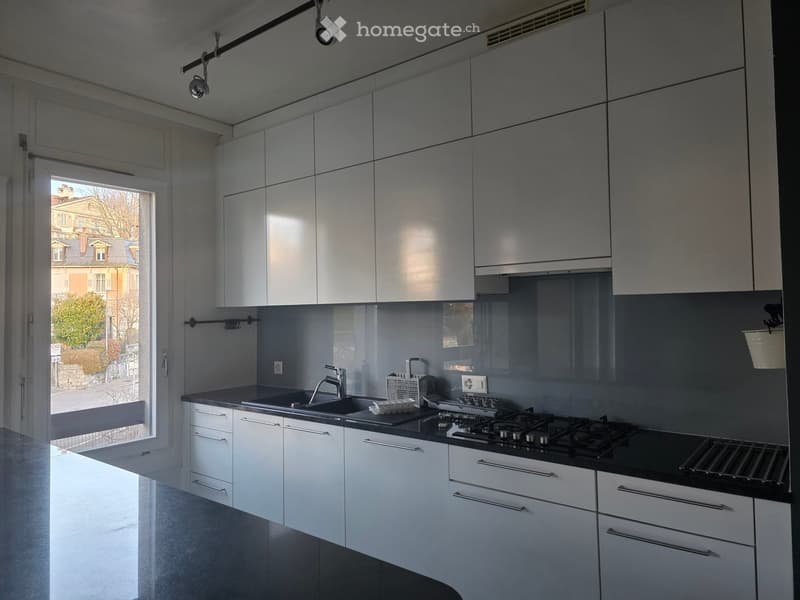 modern kitchen, granite countertop, white cabinets, stainless steel appliances, large window with balcony access