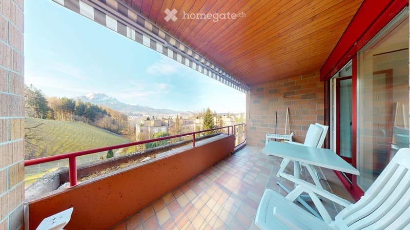 terraced balcony, tiled floor, furnished with white chairs and table, wooden ceiling, overlooking landscape and mountains