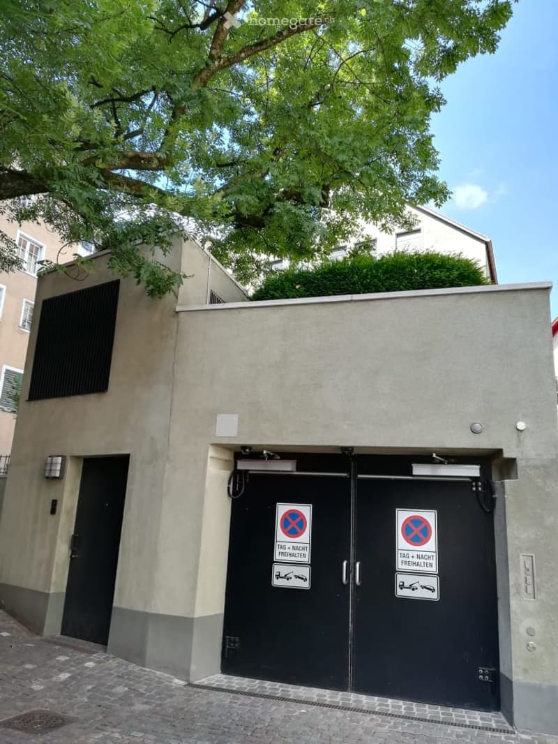 Building. A small, modern building with a garage entrance featuring double black doors and parking restrictions signs.