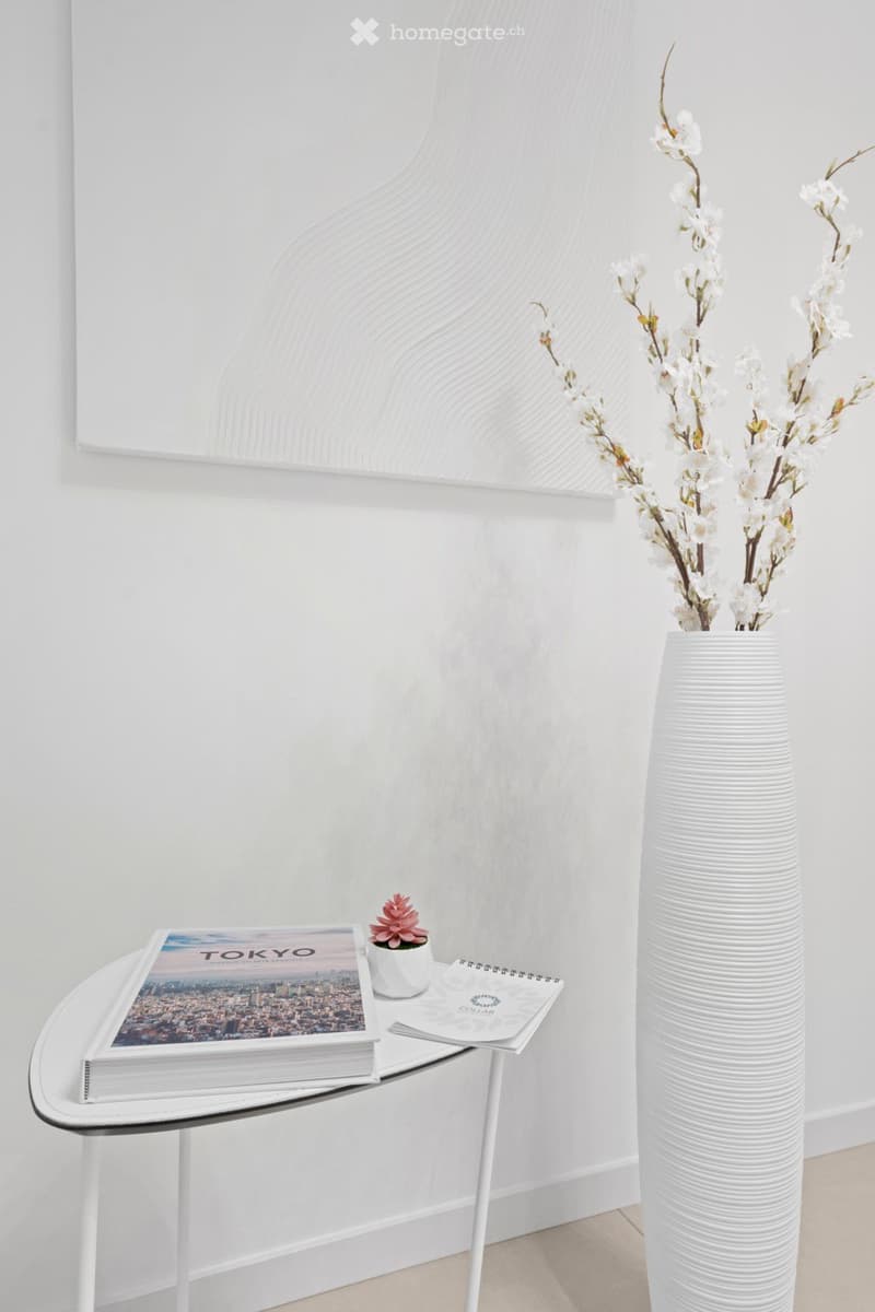 oval shaped desk, white table, white vase, flower arrangement, a book about Tokyo, notebook