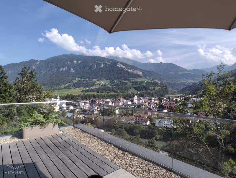 glass railing, wooden floor, green plant in a pot, panoramic view of mountains and town