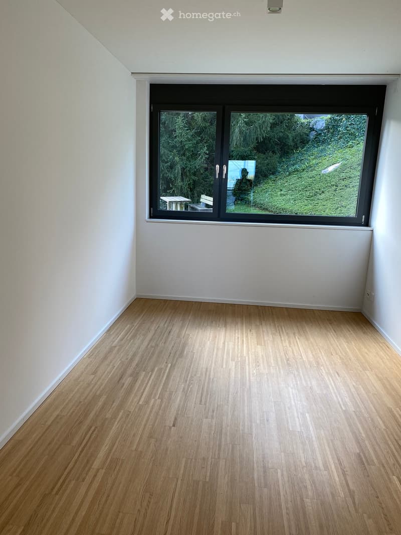 Empty room with white walls, wooden floor, and a large window.