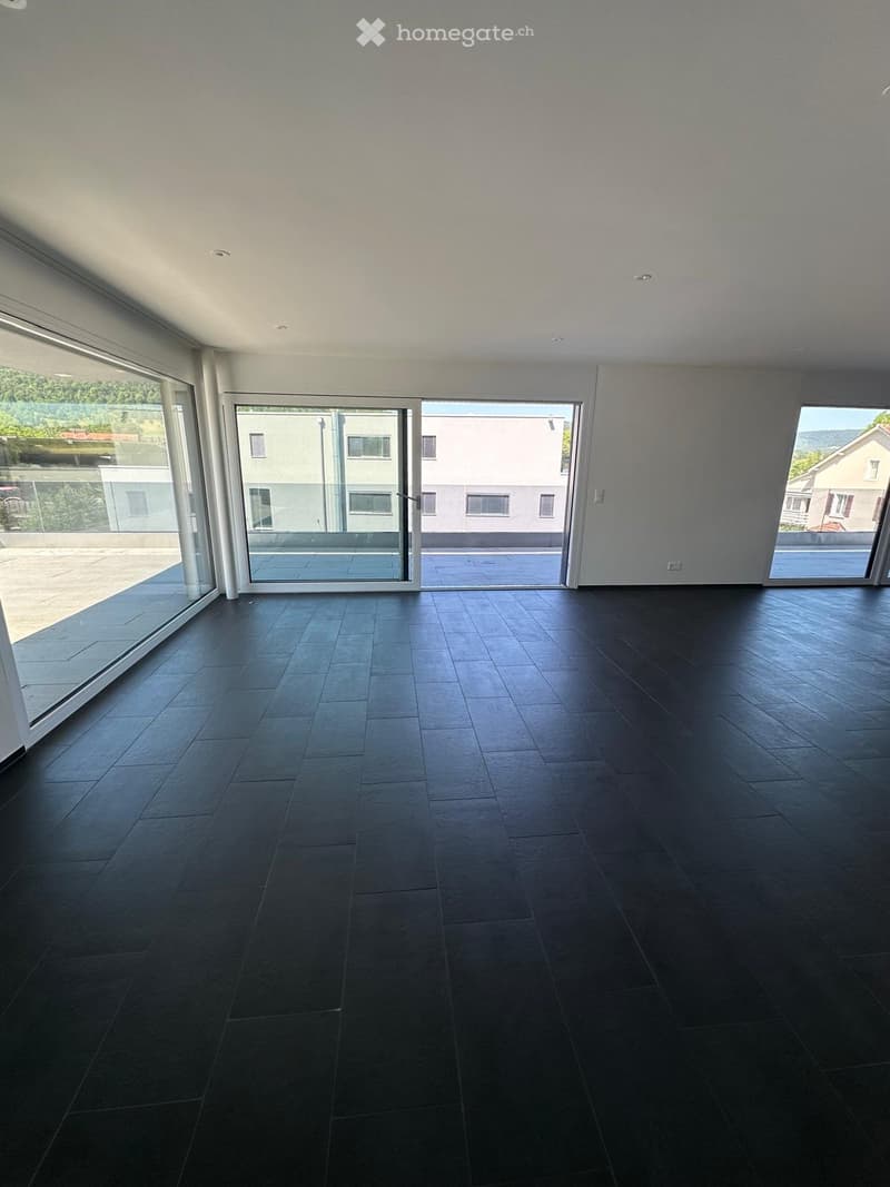 Empty room with dark tiled flooring, large glass sliding doors leading to a balcony, and white walls.